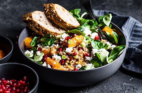 A salad containing leafy greens, fruit, and two slices of whole grain bread